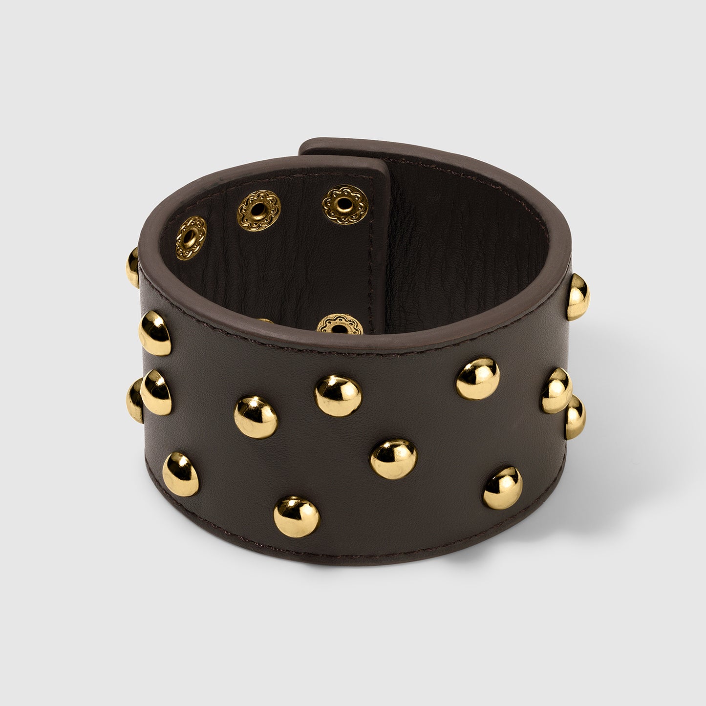 Brown leather cuff bracelet featuring gold dome studs and snap-button closures, showcasing both the exterior studded design and the interior detailing on a light gray background.