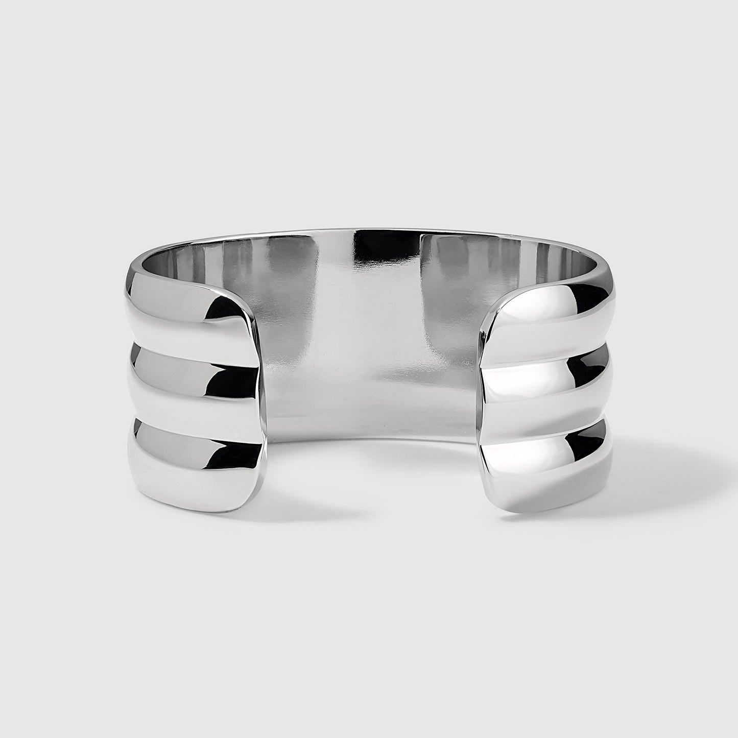 Interior view of a silver cuff bracelet showcasing its smooth, polished finish and open-ended design with three stacked horizontal bands on each side, displayed on a light gray background
