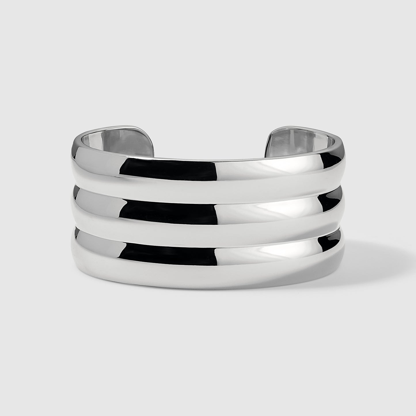 Wide silver cuff bracelet with a polished, reflective finish and three stacked horizontal bands, displayed on a light gray background. Modern and minimalist design suitable for everyday wear or special occasions.